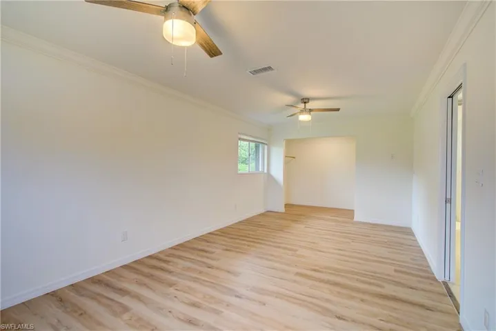 Spare room with ceiling fan, light hardwood / wood-style flooring, and crown molding