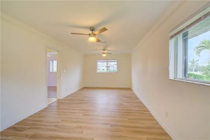 Empty room with light wood-type flooring, ceiling fan, and ornamental molding