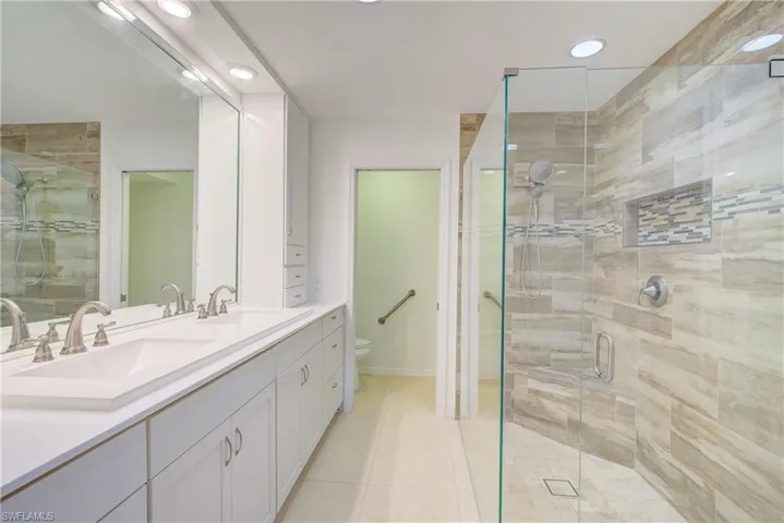 Bathroom featuring tile patterned floors, an enclosed shower, vanity, and toilet