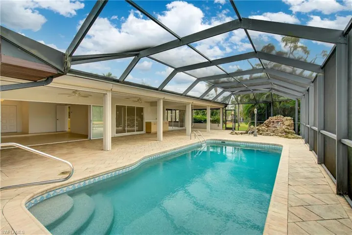 View of swimming pool featuring ceiling fan, a lanai, and a patio area