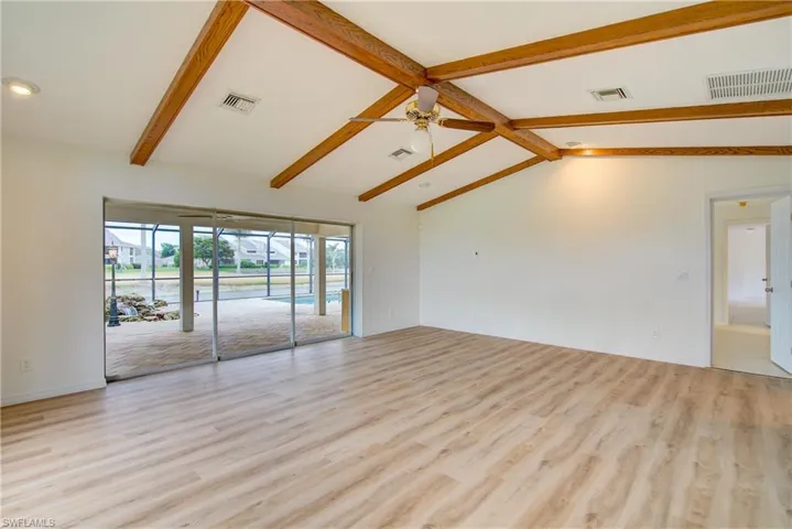 Empty room featuring high vaulted ceiling, ceiling fan, light hardwood / wood-style flooring, and beamed ceiling