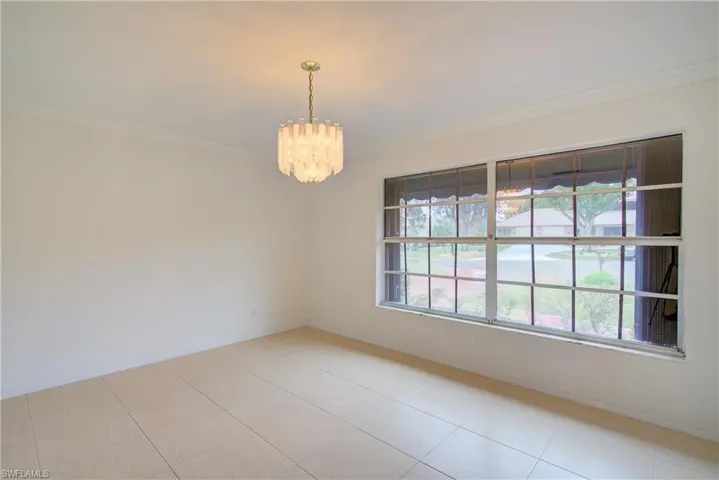 Unfurnished room featuring ornamental molding, a chandelier, and light tile patterned flooring