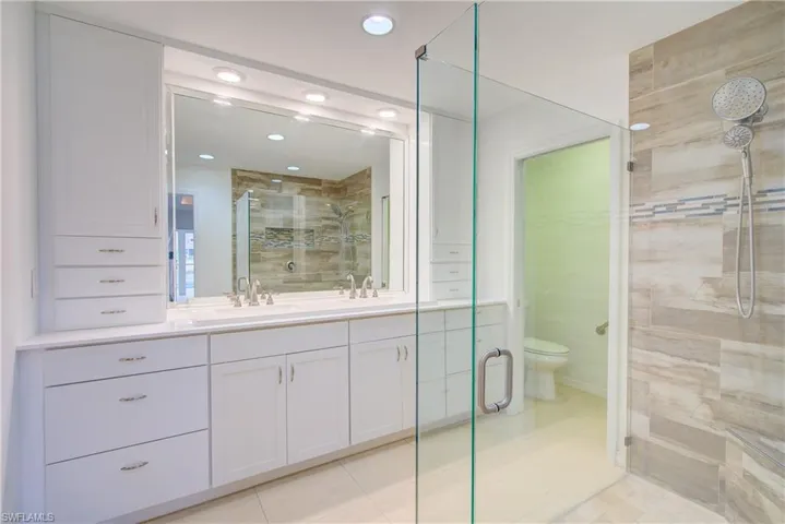 Bathroom featuring tile patterned floors, an enclosed shower, vanity, and toilet