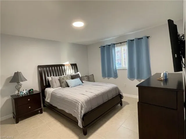 Bedroom featuring light tile patterned floors and baseboards