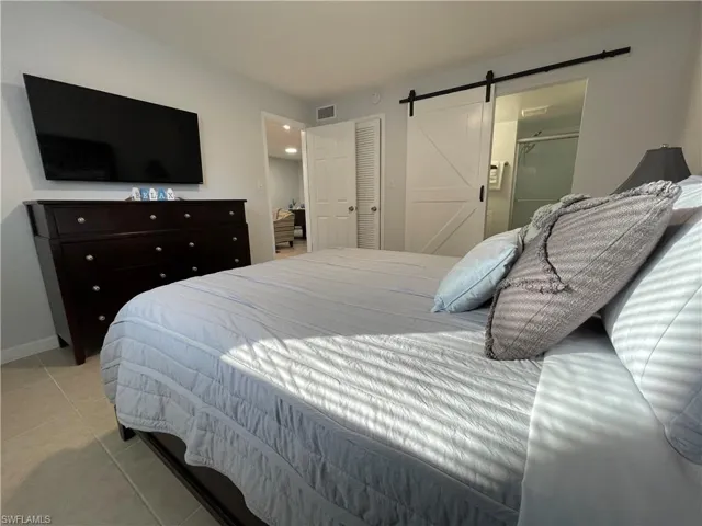 Tiled bedroom with a barn door, ensuite bathroom, and a closet