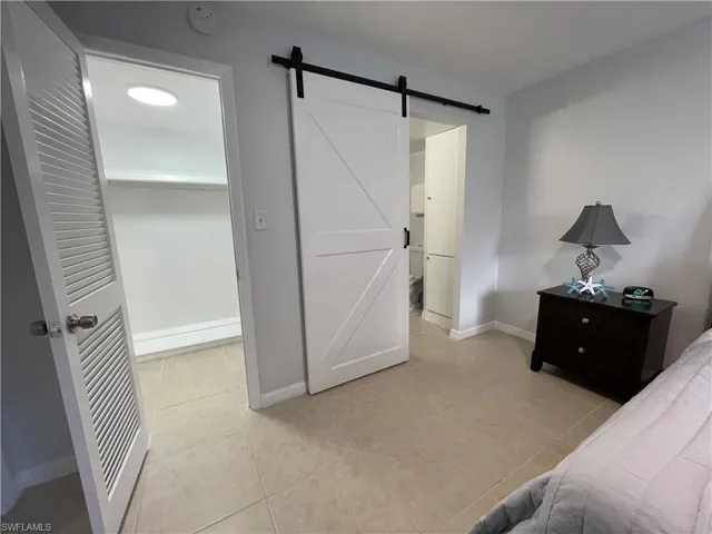 Bedroom featuring a walk in closet, a barn door, and light tile patterned floors