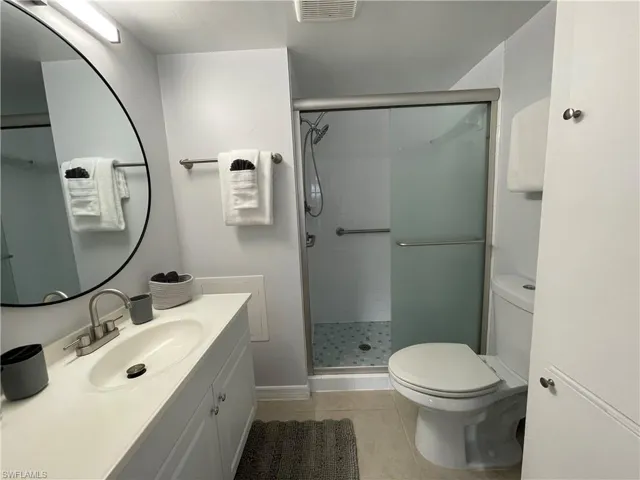 Full bath featuring vanity, light tile patterned flooring, and a stall shower