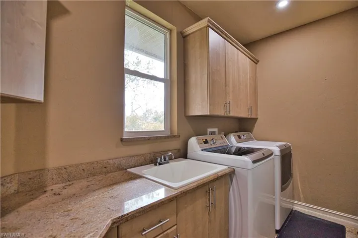 Clothes washing area with cabinets, separate washer and dryer, and sink