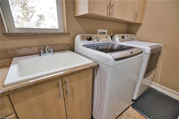 Laundry room with sink, cabinets, washer and dryer, and tile patterned floors