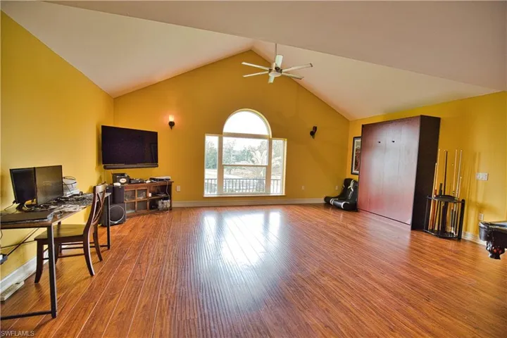 Office area with hardwood / wood-style flooring, high vaulted ceiling, and ceiling fan