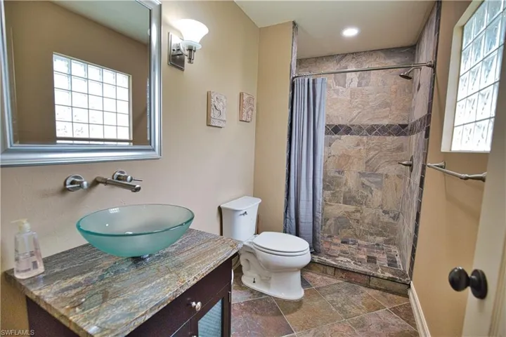Bathroom with tile patterned flooring, curtained shower, toilet, and vanity