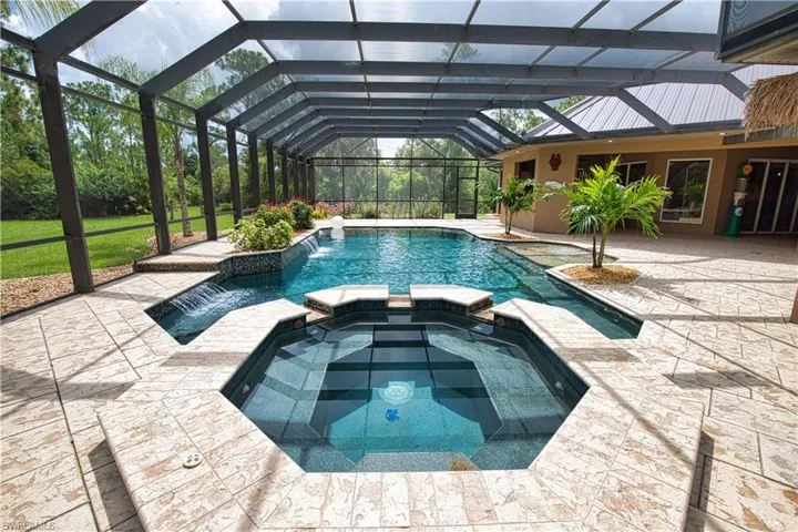 View of swimming pool with an in ground hot tub, a lanai, pool water feature, and a patio