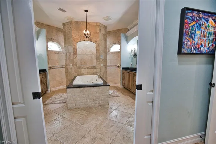 Bathroom featuring vanity, tile patterned flooring, tiled bath, and tile walls
