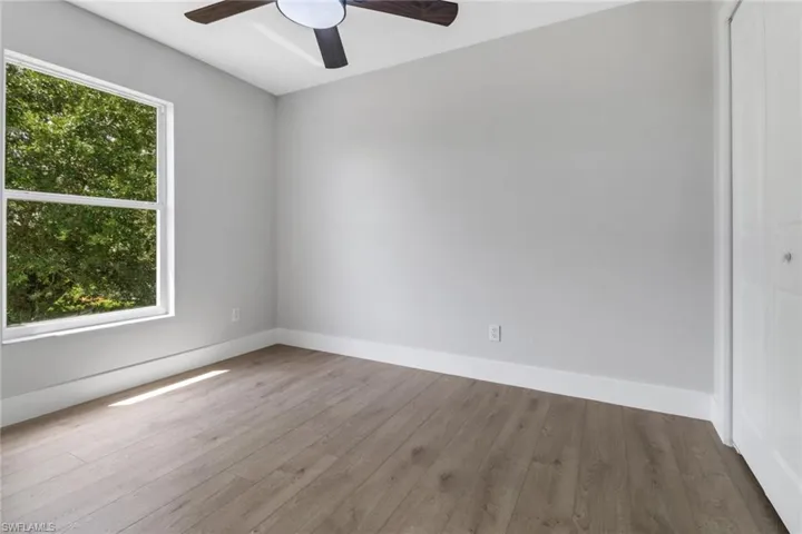 Spare room featuring a healthy amount of sunlight, ceiling fan, and wood-type flooring
