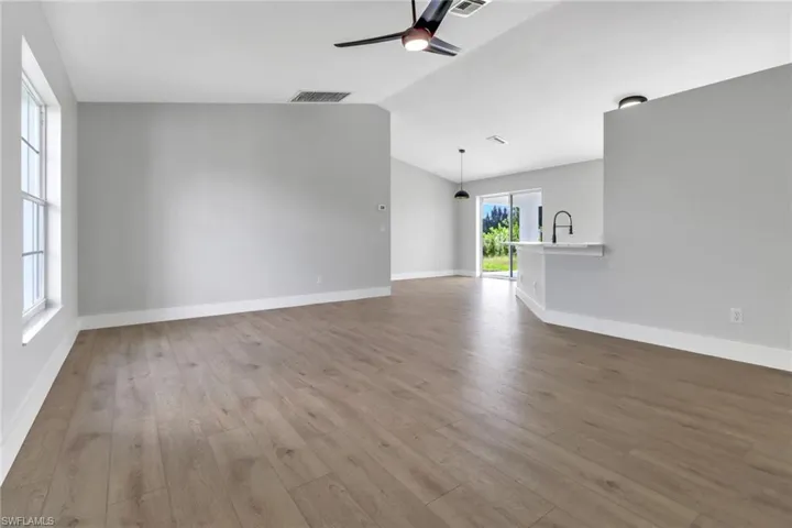 Unfurnished living room featuring lofted ceiling, ceiling fan, sink, and light hardwood / wood-style flooring