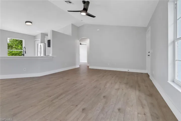 Unfurnished living room featuring lofted ceiling, ceiling fan, and light wood-type flooring