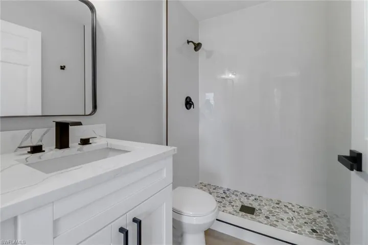 Bathroom featuring walk in shower, toilet, and vanity