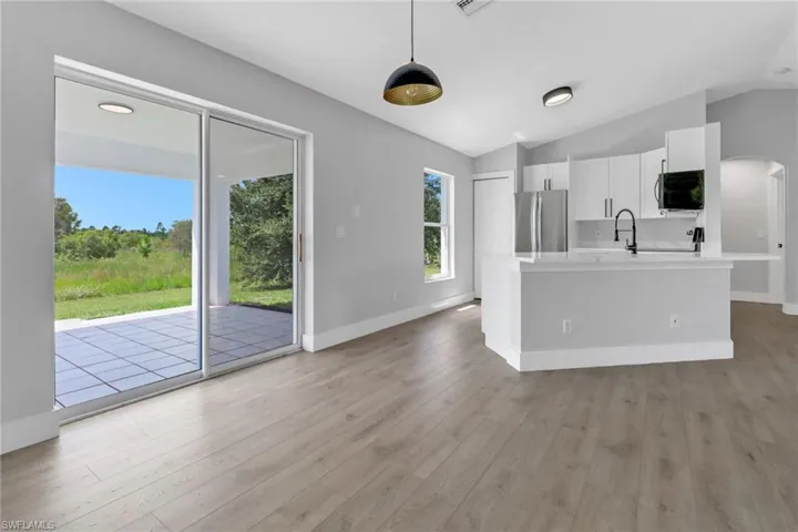 Kitchen featuring white cabinetry, stainless steel fridge, vaulted ceiling, and a wealth of natural light