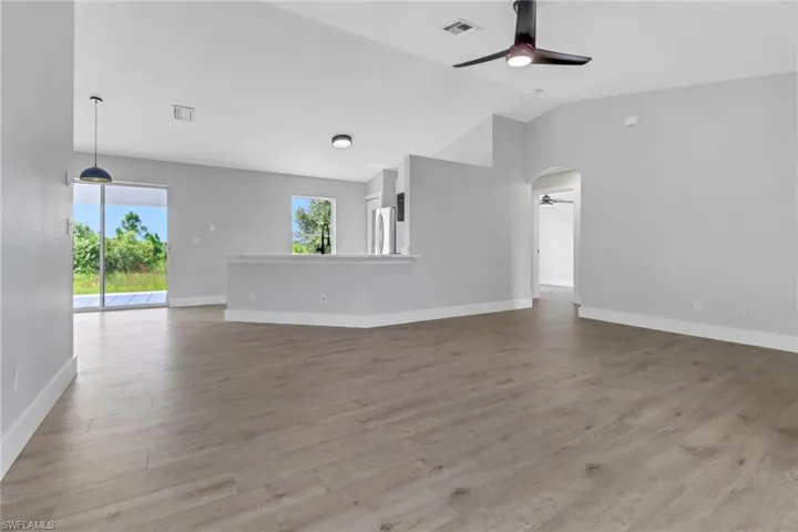 Unfurnished living room with vaulted ceiling, light hardwood / wood-style flooring, and ceiling fan