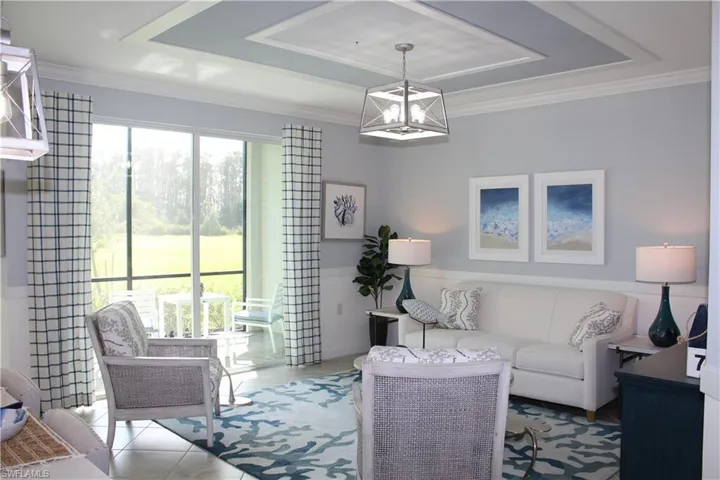 Tiled living room with a chandelier, a tray ceiling, and crown molding