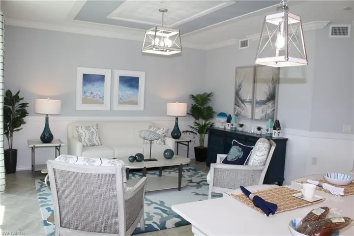 Tiled living room featuring a raised ceiling and ornamental molding