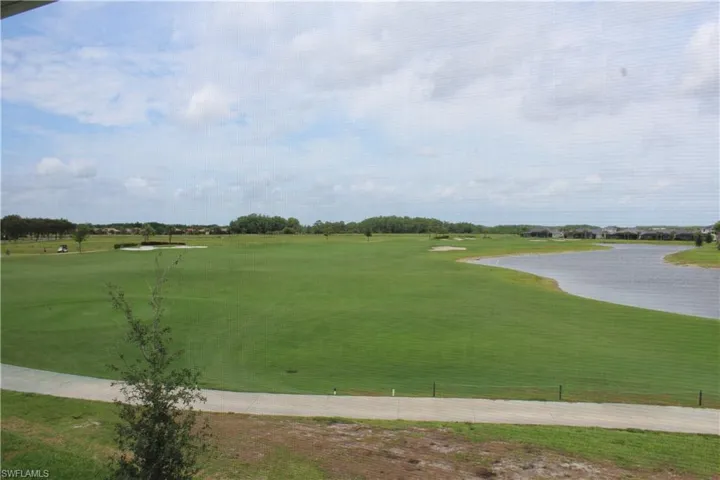 View of property's community with golf course view, a yard, and a water view
