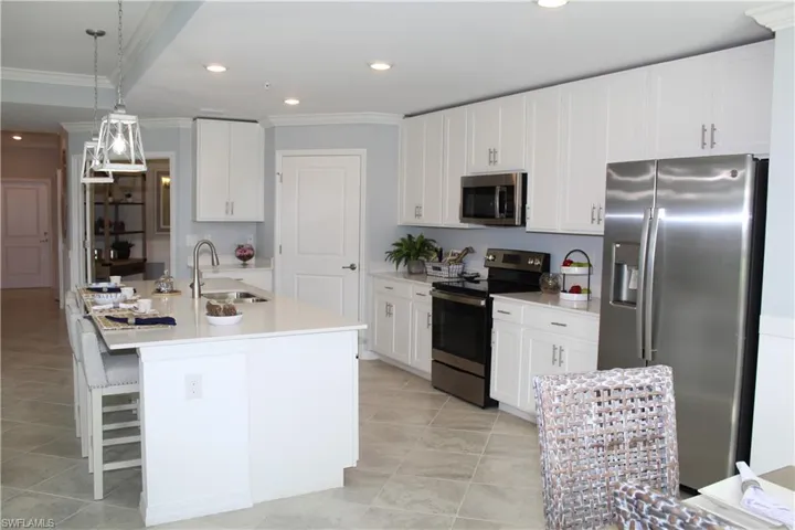 Kitchen featuring appliances with stainless steel finishes, a sink, ornamental molding, light tile patterned flooring, and light countertops