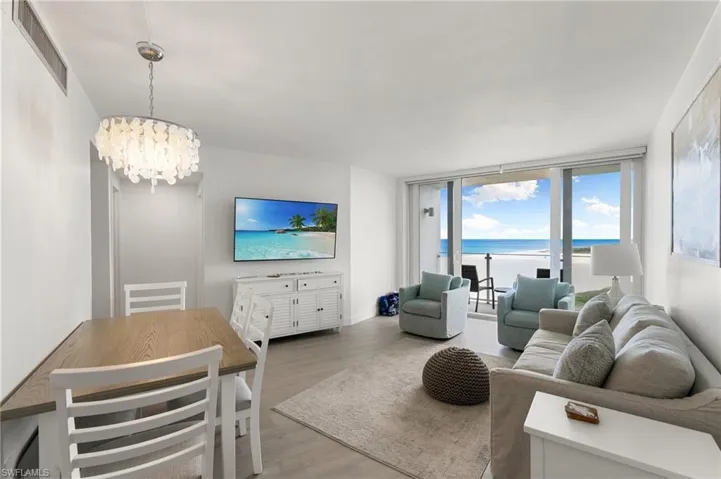 Living room with a wall of windows, wood finished floors, visible vents, and an inviting chandelier