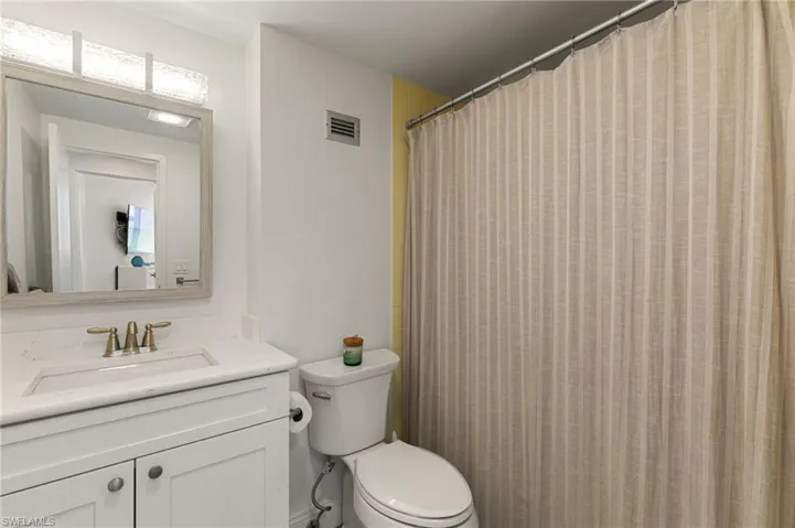 Full bath featuring toilet, visible vents, and vanity