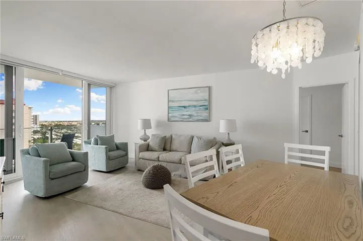 Living room with a chandelier, expansive windows, and wood finished floors
