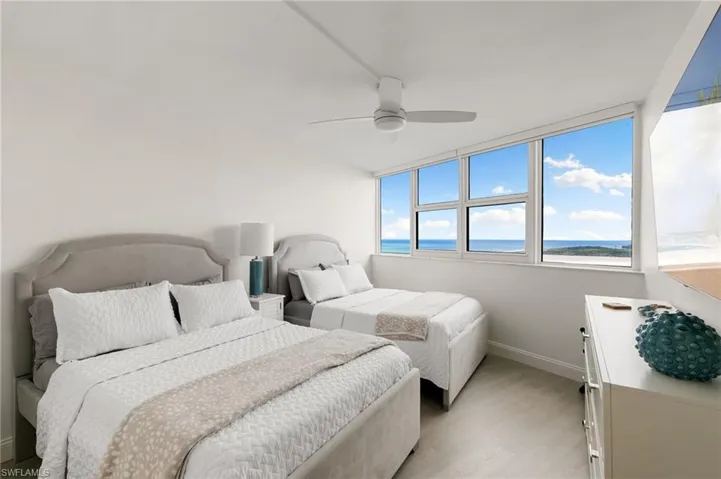 Bedroom with a water view, ceiling fan, light wood-style flooring, and baseboards