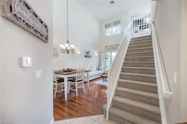 Stairs with a towering ceiling, tile patterned flooring, and a chandelier