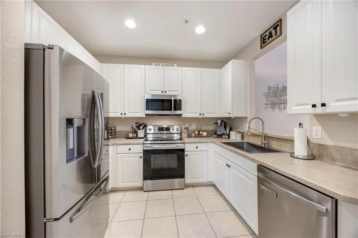 Kitchen featuring stainless steel appliances, light countertops, white cabinetry, recessed lighting, and light tile patterned flooring
