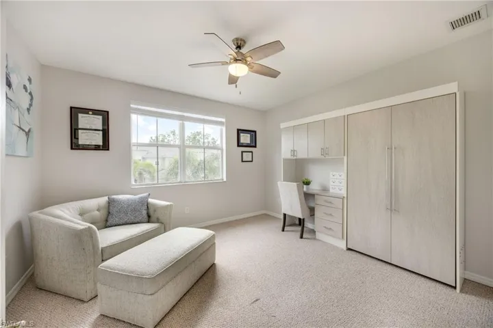Sitting room featuring light carpet, ceiling fan, and built in study area