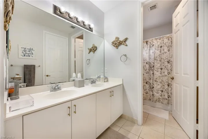 Bathroom with double vanity, a shower with curtain, and light tile patterned flooring