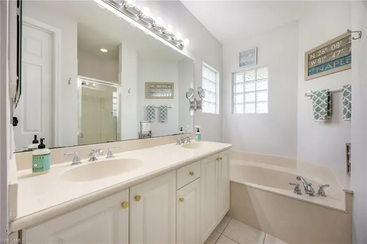 Full bath featuring a stall shower, double vanity, a bath, and light tile patterned floors