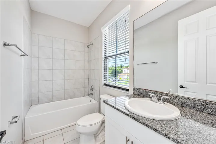 Full bathroom with tiled shower / bath combo, tile patterned flooring, vanity, and toilet