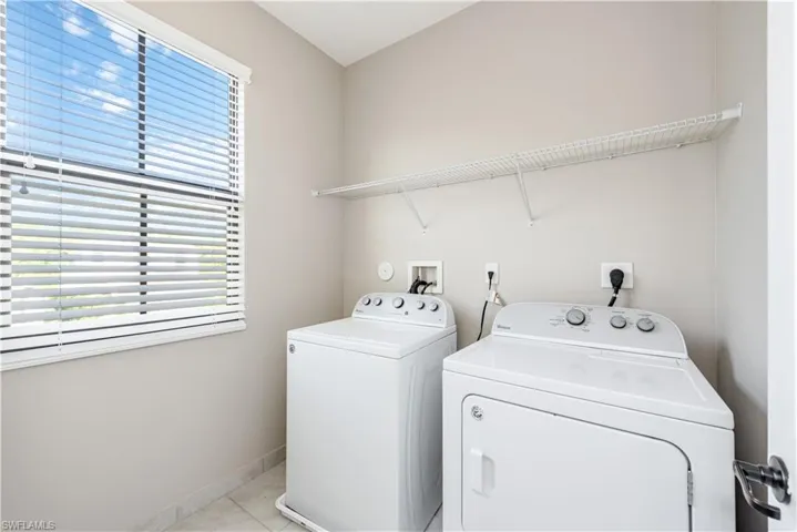 Laundry room featuring light tile patterned floors and washing machine and clothes dryer