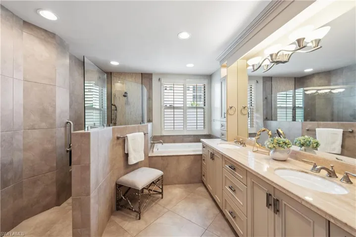 Bathroom with tile walls, tile flooring, dual vanity, and plus walk in shower