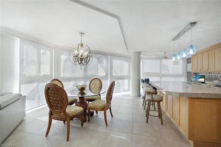 Tiled dining room with rail lighting, a chandelier, and ornate columns