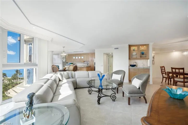 Living room with light tile patterned flooring, ornamental molding, and an inviting chandelier