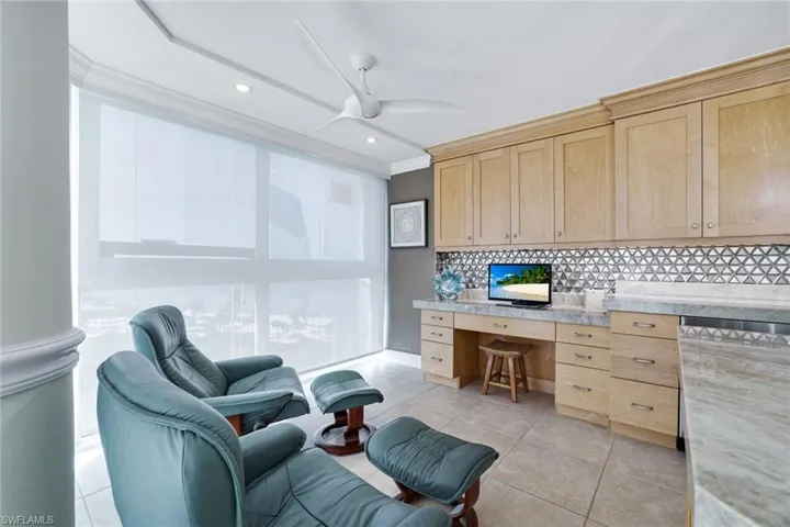 Office featuring built in desk, crown molding, light tile patterned flooring, and ceiling fan