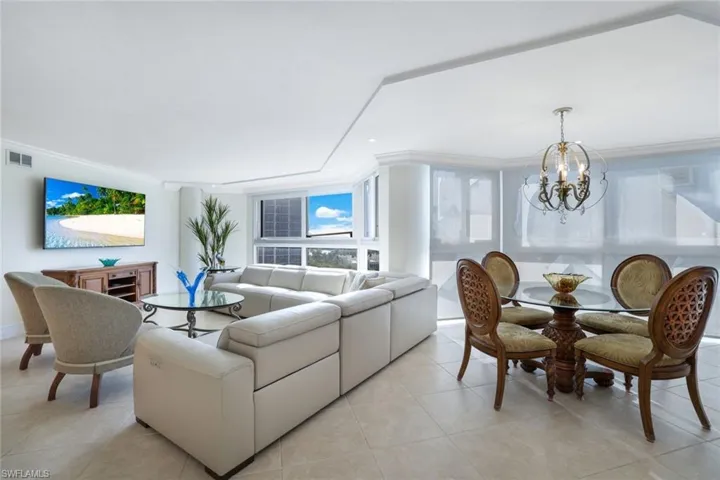 Tiled living room with ornamental molding and a chandelier