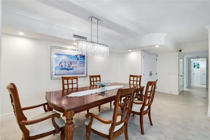 Tiled dining room with ornamental molding and an inviting chandelier