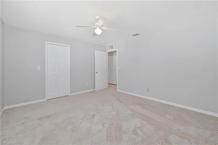 Unfurnished bedroom featuring light carpet, a ceiling fan, and a closet