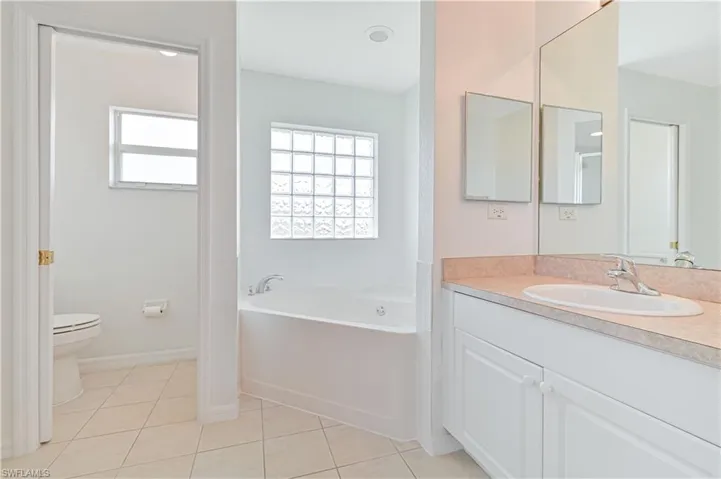 Bathroom with vanity, a garden tub, and light tile patterned flooring