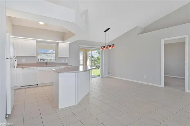 Kitchen with white cabinetry, light countertops, white appliances, a kitchen island, and pendant lighting