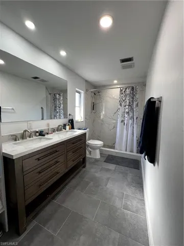 Master Bathroom with double-sink vanity, curtained shower, and toilet