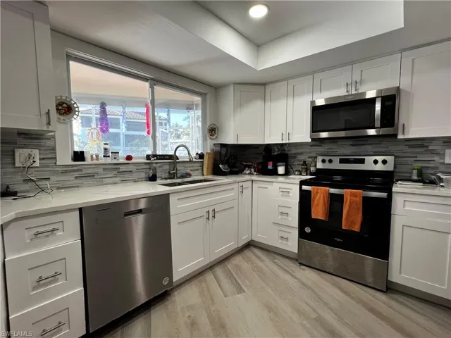 Kitchen featuring light stone countertops, appliances with stainless steel finishes, sink, and a picture window