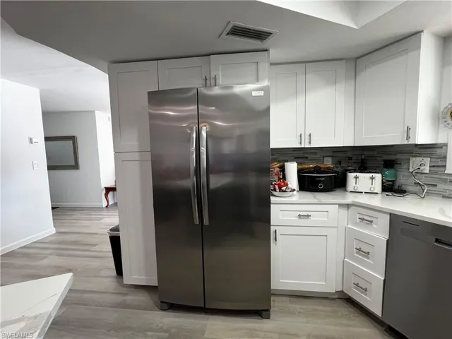 Kitchen with stainless steel refrigerator, backsplash, dishwasher, and a picture window
